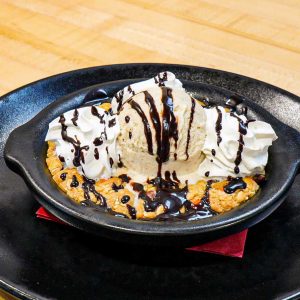 Monster Skillet Cookie with Vanilla Ice Cream, Whipped Cream, and Chocolate Sauce. **contains peanut, wheat, dairy, egg**