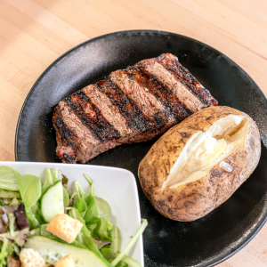 A classic Steakhouse dinner of New York Strip, Baked Potato and a Side Salad.